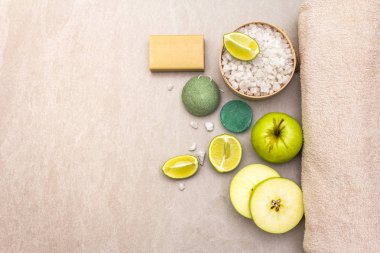 Spa konsepti, doğal malzemeler. Banyo havlusu, limonlu deniz tuzu, elma, zeytin ve nane sabunu, sünger. Taş bir arkaplanda, üst görünüm