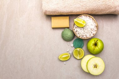 Spa konsepti, doğal malzemeler. Banyo havlusu, limonlu deniz tuzu, elma, zeytin ve nane sabunu, sünger. Taş bir arkaplanda, üst görünüm