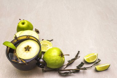 Meyve çayı konsepti. Taze limon ve elma, kuru otlar. Taş zemin üzerinde cam kahverengi bardak