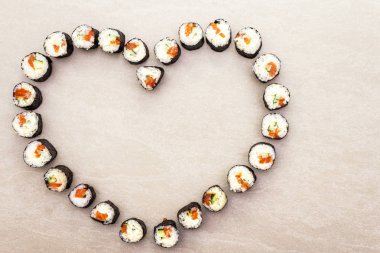 Romantik kalp suşi yemeği. Somon, Philadelphia peyniri ve salatalıklı rulo. Sevgililer Günü ya da 8 Mart için konsept. Taş arkaplan, üst görünüm