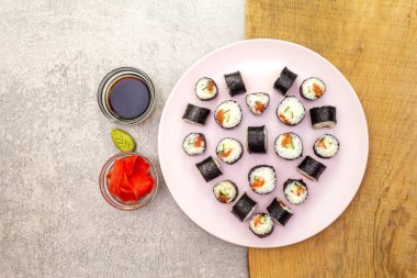 Romantik kalp suşi yemeği. Maki, zencefilli, wasabi ve soya soslu, pembe tabakta. Sevgililer Günü ya da 8 Mart için konsept. Taş ve ahşap zemin, üst manzara