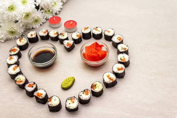 Romantyczna kolacja sushi. Maki bułki z imbirem, wasabi i sosem sojowym, świece i kwiaty. Koncepcja na Walentynki lub 8 marca. Tło kamienia — Zdjęcie stockowe