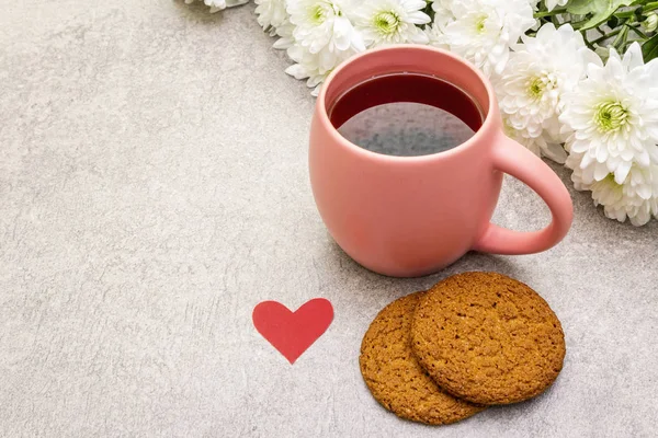 Petit déjeuner romantique concept. Une tasse de thé noir, des biscuits à l'avoine, un bouquet de chrysanthèmes. Pour la Saint-Valentin ou le 8 mars, sur fond de pierre — Photo