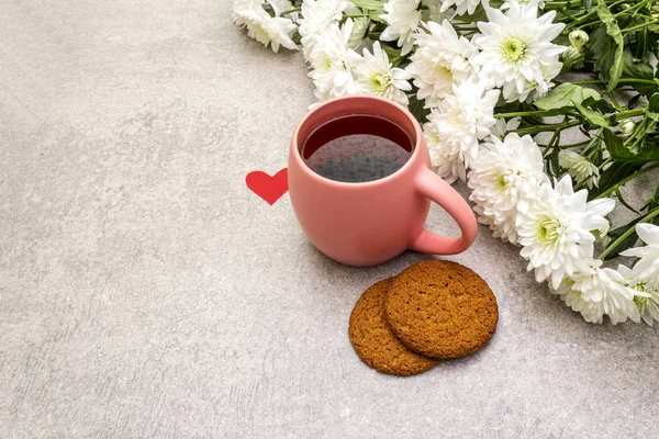Petit déjeuner romantique concept. Une tasse de thé noir, des biscuits à l'avoine, un bouquet de chrysanthèmes. Pour la Saint-Valentin ou le 8 mars, sur fond de pierre — Photo