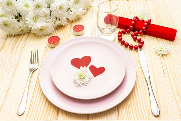 Romantic dinner concept. Valentines day, 8th march or wedding. Table setting, love hearts, gift and flowers. On wooden background Stock Picture