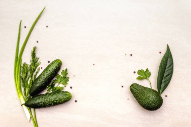 Yeşil sebzeler ve şifalı bitkiler. Avokado, avokado yaprağı, salatalık, kabak, maydanoz, dereotu, yeşil soğan tüyü, biber karışımı. Taş zeminde, düz yerde, en üstte.