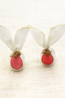 Paskalya tavşanı (tavşan) yumurta konsepti, masa düzenlemesi. Kumaş kumaş kumaş peçetesi (branda) üzerinde pembe (pembe) yumurtalar