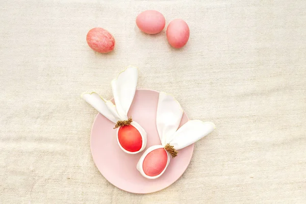 イースターウサギ(ウサギ)卵の概念は、テーブルの配置の装飾。ピンク(バラ色)卵とプレート上の布ヴィンテージリネンナプキン(キャンバス)の背景、トップビュー — ストック写真