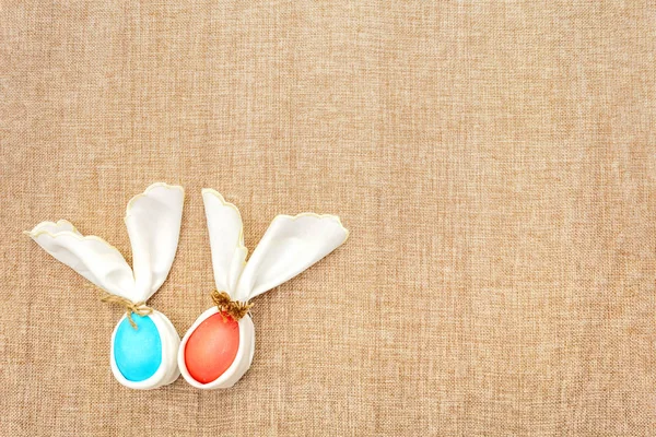 Conejo de Pascua (conejo) concepto de huevo, decoración disposición de la mesa. Huevos rosados (rosados) y azules con servilletas sobre fondo de tela (lino), vista superior —  Fotos de Stock