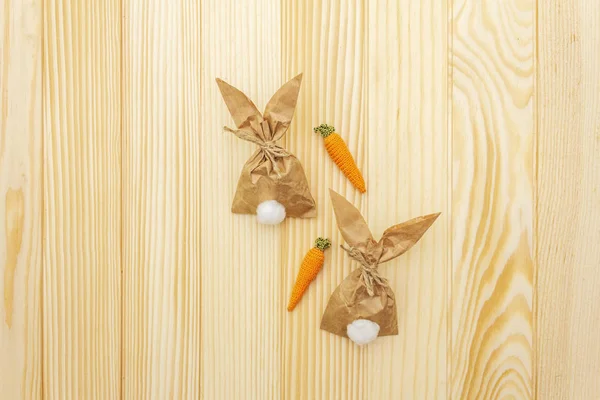 Πάσχα λαγουδάκι (κουνέλι) χάρτινο περιτύλιγμα δώρου με πλεκτό καρότα ιδέα. Χειροτεχνία (σπιτική) έννοια για παιδιά (παιδιά). Σε ξύλινο φόντο, πάνω όψη — Φωτογραφία Αρχείου