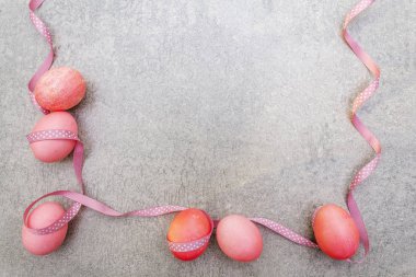 Paskalya konsepti pembe (pembe) yumurtalar ve saten polka noktalı kurdeleler. Taş zeminde. Çerçeve, üst görünüm