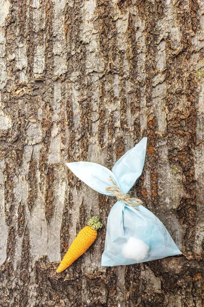 Lapin de Pâques (lapin) emballage cadeau en papier avec idée de carotte tricotée. Artisanat (fait maison) concept pour enfants (enfants). Sur fond d'écorce de bois — Photo