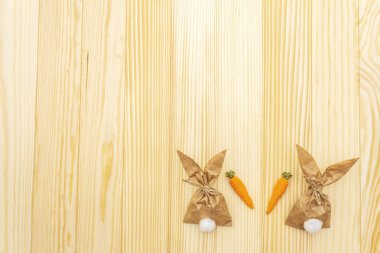 Paskalya tavşanı (tavşan) kağıt hediye paketi ve örgü havuç fikri. Çocuklar için el yapımı (ev yapımı) konsept. Ahşap arka planda, üst görünümde