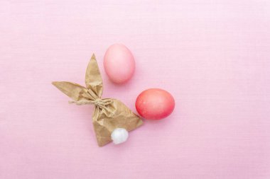 Paskalya tavşanı (tavşan) kağıt yumurta paketleme fikri. Çocuklar için el yapımı (ev yapımı) konsept. Pembe kumaş üzerine (keten) arka plan