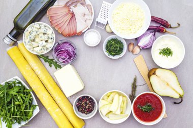 Pizza, kiş ve lezzetli turtalar için malzemeler. Hamur, et, mavi peynir, mozzarella, domates (ketçap), ekşi krema sosu, armut, soğan, zeytinyağı, otlar, baharatlar. Taş arkaplan, üst görünüm