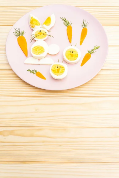 Zajączek wielkanocny (królik) i jaj kurzych dzieci (dzieci) koncepcja żywności. Z marchewką na różowym talerzu. Kontekst drewniany — Zdjęcie stockowe