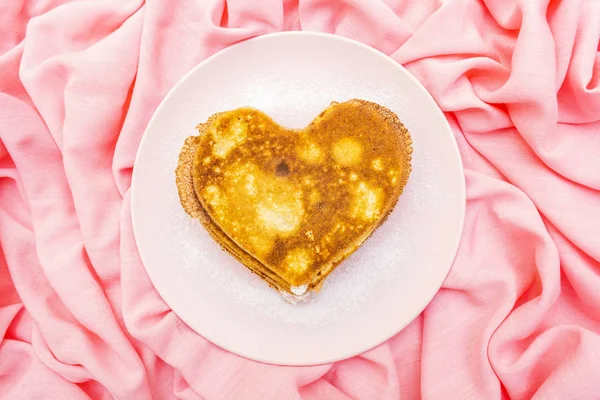 Crêpes en forme de coeur pour le petit déjeuner romantique sur assiette rose. Concept de Shrovetide (carnaval). Sur fond lin tissu rose, vue de dessus — Photo