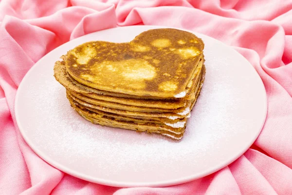 Heart shaped pancakes for romantic breakfast on rosy plate. Shrovetide (carnival) concept. On pink cloth linen background — Stock Photo, Image