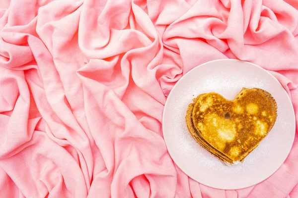 Crêpes en forme de coeur pour le petit déjeuner romantique sur assiette rose. Concept de Shrovetide (carnaval). Sur fond lin tissu rose, vue de dessus — Photo
