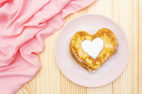 Crêpes en forme de coeur pour le petit déjeuner romantique. Concept de Shrovetide (carnaval). Sur fond bois avec toile de lin rose, vue sur le dessus — Photo