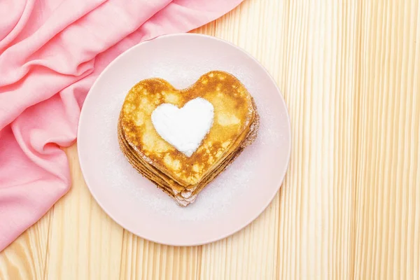 Crêpes en forme de coeur pour le petit déjeuner romantique. Concept de Shrovetide (carnaval). Sur fond bois avec toile de lin rose, vue sur le dessus — Photo