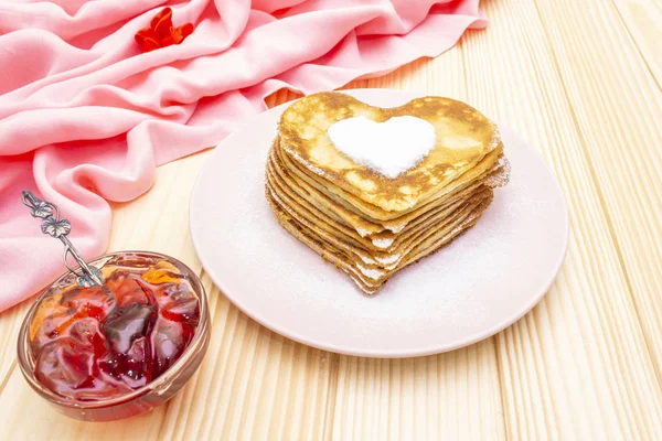 Crêpes en forme de coeur pour le petit déjeuner romantique avec confiture de fraises. Concept de Shrovetide (carnaval). Sur fond bois avec toile de lin rose — Photo