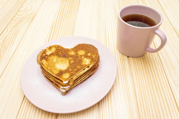 Heart shaped pancakes for romantic breakfast with strawberry jam and black tea. Shrovetide (carnival) concept. On wooden background — Stock Photo, Image