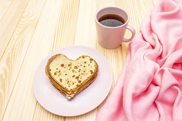 Panqueques en forma de corazón para un desayuno romántico con mermelada de fresa y té negro. Concepto de Shrovetide (carnaval). Sobre fondo de madera — Foto de Stock