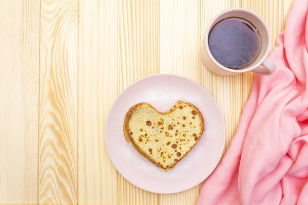 Crêpes en forme de coeur pour un petit déjeuner romantique avec confiture de fraises et thé noir. Concept de Shrovetide (carnaval). Sur fond bois, vue de dessus — Photo