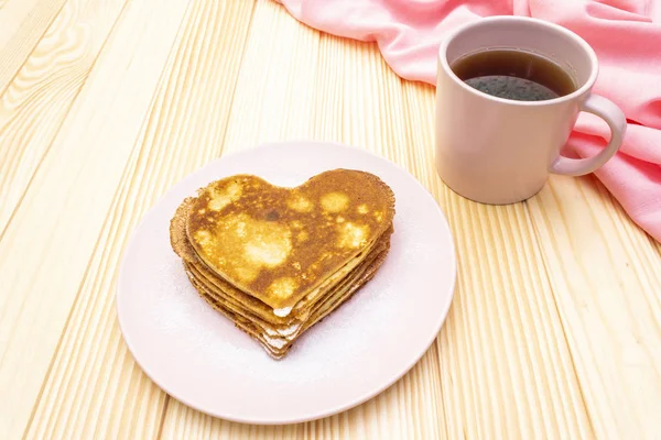 Panqueques en forma de corazón para un desayuno romántico con mermelada de fresa y té negro. Concepto de Shrovetide (carnaval). Sobre fondo de madera — Foto de Stock