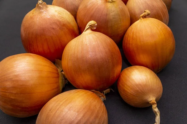 Vários grandes bulbos amarelos cebola em um fundo preto. Vista superior . — Fotografia de Stock