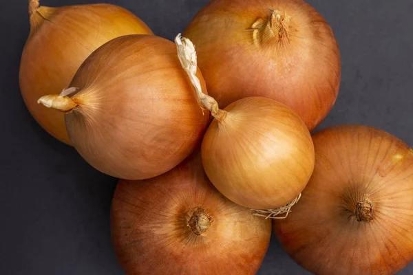 Vários grandes bulbos amarelos cebola em um fundo preto. Vista superior . — Fotografia de Stock