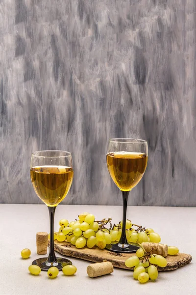Wine glasses, fresh grapes and corks on wooden chopping board. Wine bar, winery, wine tasting concept