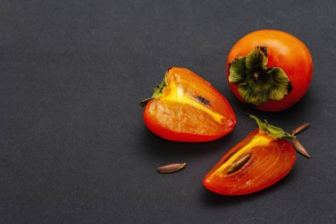 Olgunlaşmış tek bir hurma. Taze meyve, yarısı dilimlenmiş, tohum. Mat siyah arkaplanda izole edilmiş