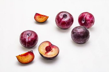 Olgun mor erikler. Taze meyve, yarısı dilimlenmiş, tohum. Beyaz arkaplanda izole