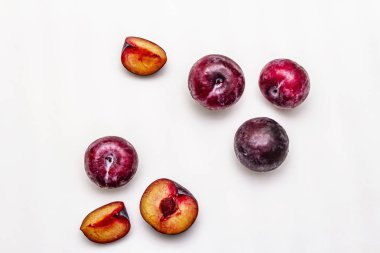 Olgun mor erikler. Taze meyve, yarısı dilimlenmiş, tohum. Beyaz arkaplanda izole