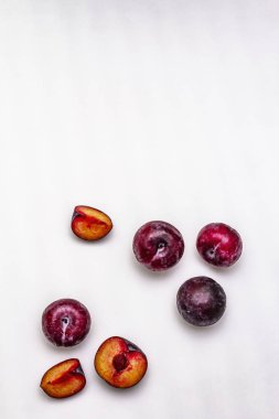 Olgun mor erikler. Taze meyve, yarısı dilimlenmiş, tohum. Beyaz arkaplanda izole