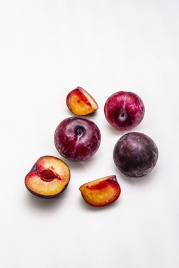 Olgun mor erikler. Taze meyve, yarısı dilimlenmiş, tohum. Beyaz arkaplanda izole
