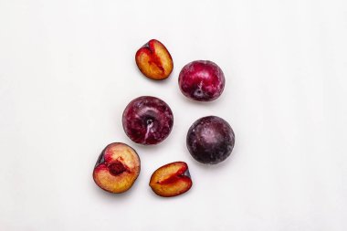 Olgun mor erikler. Taze meyve, yarısı dilimlenmiş, tohum. Beyaz arkaplanda izole