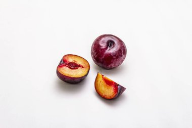 Olgun mor erikler. Taze meyve, yarısı dilimlenmiş, tohum. Beyaz arkaplanda izole