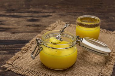 Saf ya da desi ghee (ghi), eritilmiş tereyağı. Sağlıklı yağlar kurşun geçirmez diyet konsepti veya paleo tarzı plan. Cam kavanoz, gümüş kaşık ve eski püskü kumaş. Tahta kaplama arka plan