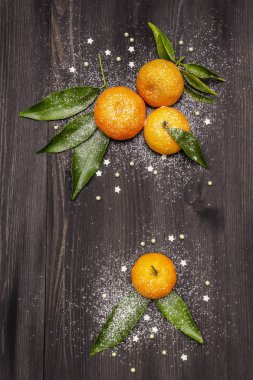 Taze taze mandalinalar ve yapraklar. Yeni yıl ya da Noel ağacının arka planında yapay kar var. Neşeli ruh hali konsepti