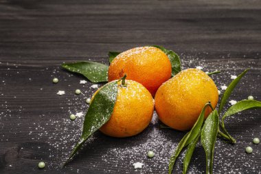 Taze taze mandalinalar ve yapraklar. Yeni yıl ya da Noel ağacının arka planında yapay kar var. Neşeli ruh hali konsepti