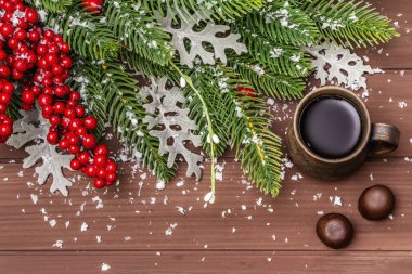 Noel kahvesi arka planı. Yeni yıl ağacı, köpek gülü, taze yapraklar, çikolata şekeri ve yapay kar. Tahta zemin