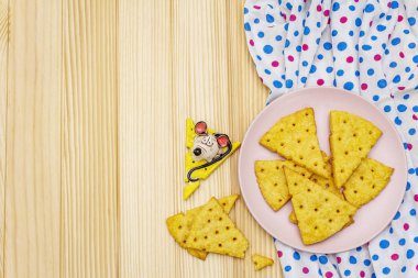 Komik çocuk kurabiyeleri. Peynirli krakerler, yeni yıl atıştırmalığı konsepti. Yemek, fare heykeli, peçete. Tahta arka plan