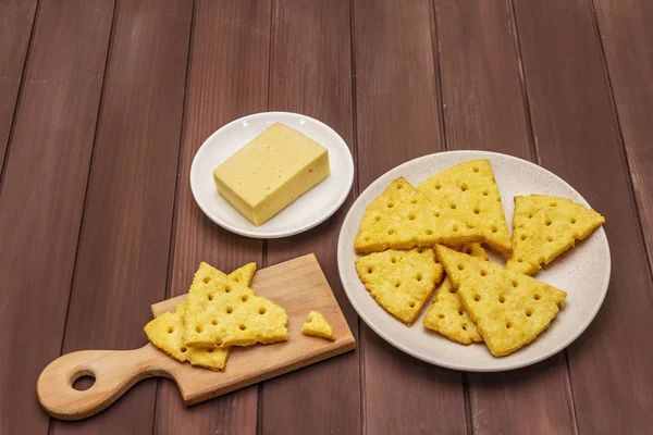 Craquelins au fromage, concept de collation salée. Cookies, morceau de fromage, planche à découper. Planches en bois fond — Photo