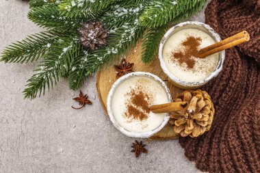Camda tarçınlı ev yapımı eggnog. Tipik Noel tatlısı. Evergreen köknar brunch 'ı, koniler, rahat ekose kumaş, yapay kar. Taş beton arka plan