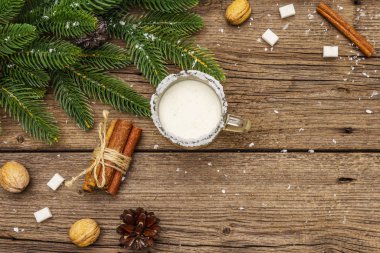 Noel eggnog likörü ya da tek kişilik kola kokteyli. Cam bardakta klasik kış içkisi, xmas süslemeleri. Evergreen dalları, tarçın, ceviz, şeker. Eski tahta arkaplan
