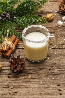 Noel eggnog likörü ya da tek kişilik kola kokteyli. Cam bardakta klasik kış içkisi, xmas süslemeleri. Evergreen dalları, tarçın, ceviz, şeker. Eski tahta arkaplan