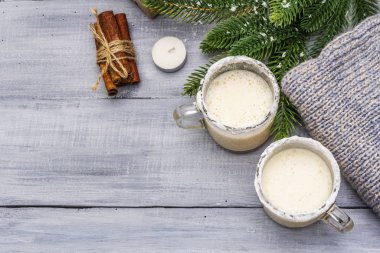 İki bardak bardakta eggnog kokteyli. Hafif ahşap masada noel süsü ile düzenlenmiş. Evergreen köknar ağacı dalı, hediye, rahat forma, yapay kar